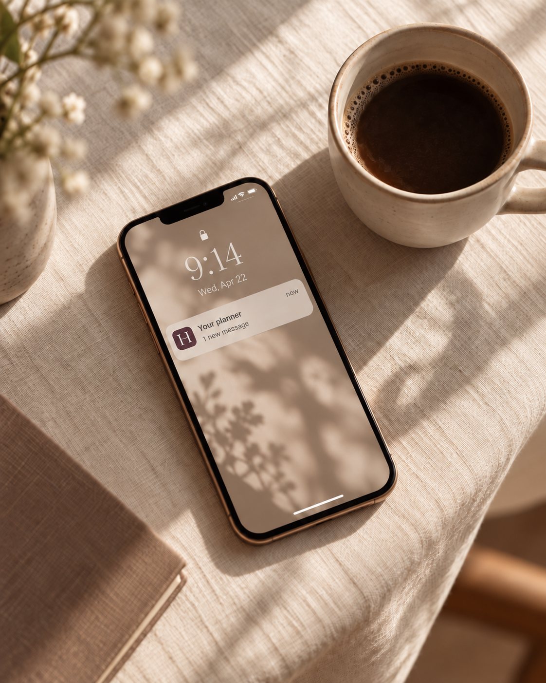 A phone on a linen tablecloth beside a cup of coffee, showing a new message from Your planner.